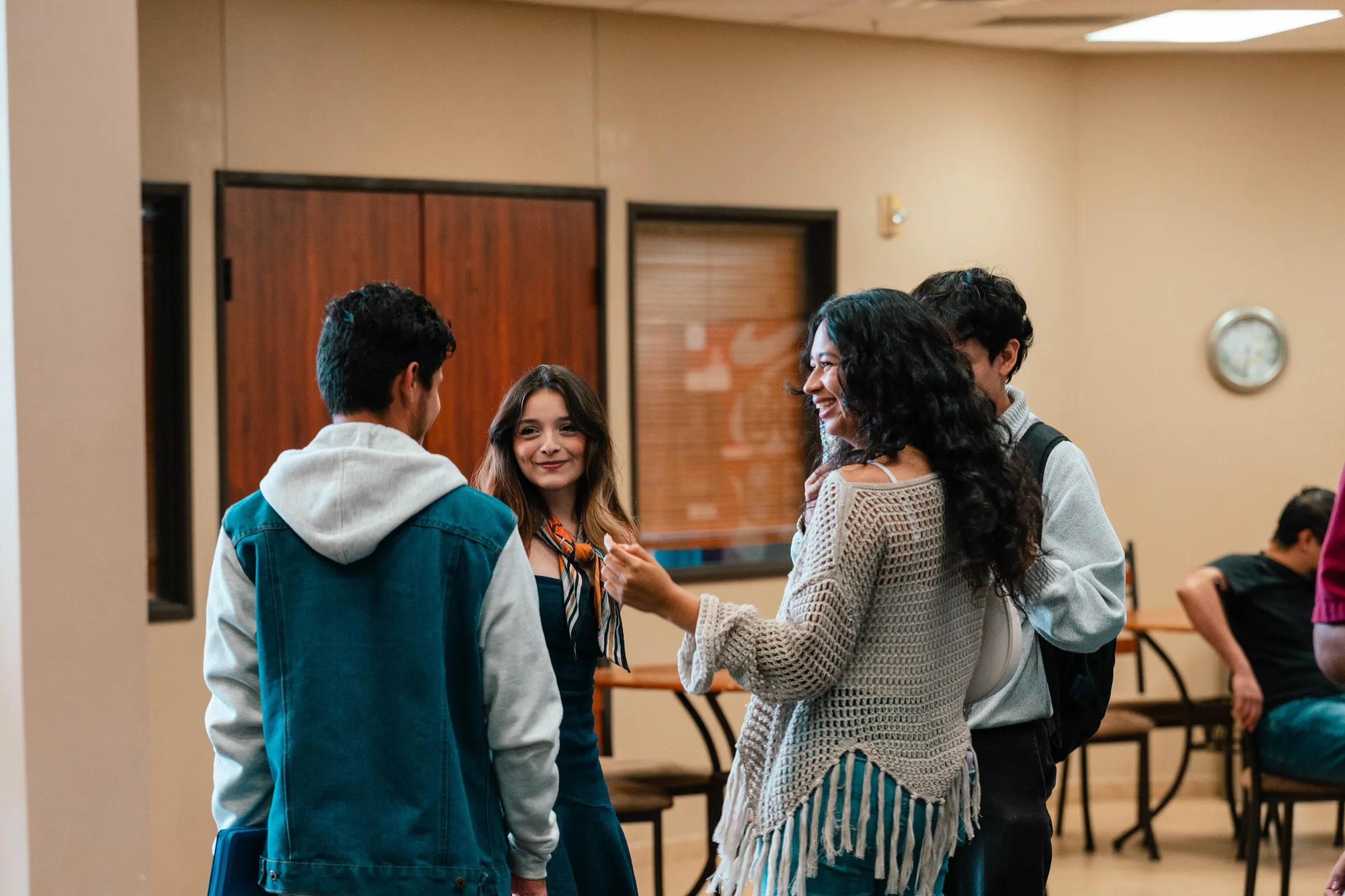Un grupo de jóvenes conversa y ríe de pie en el salón