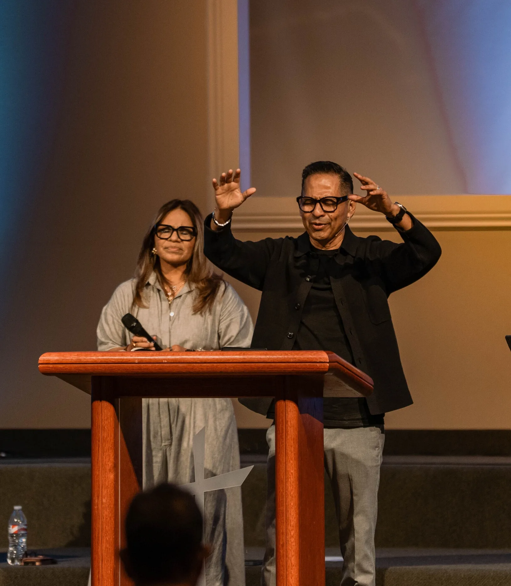 El pastor Charly ora desde el púlpito junto a Miriam, su esposa